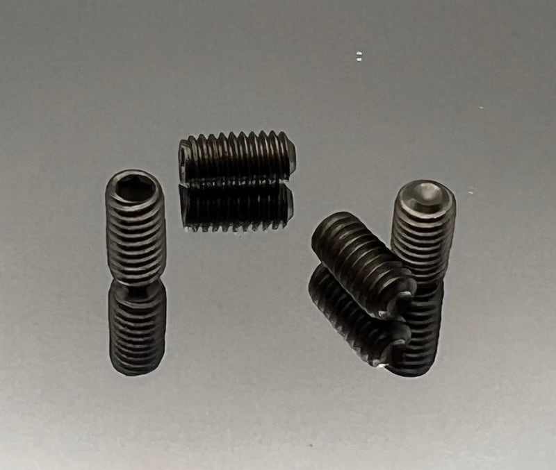 Four black metal screws on a gray reflective surface